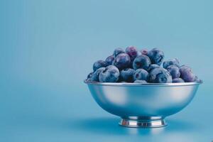 blueberries in a silver bowl isolated on a blue gradient background photo