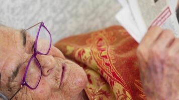 Elderly Woman is Lying on Bed and Reading Magazine Newspaper video