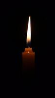 un vela es iluminado en un oscuro habitación. el vela es el solamente fuente de ligero en el habitación video