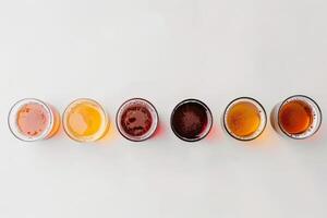 Minimalist concept of beer tasting, small glasses arranged in a row on a pristine white surface photo