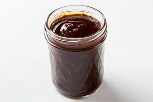 Classic barbecue sauce in a rustic mason jar, dark and smoky, isolated on a white backdrop photo