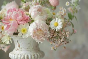 Close up of a shabby chic floral arrangement in a distressed white vase, peonies and daisies mingling photo