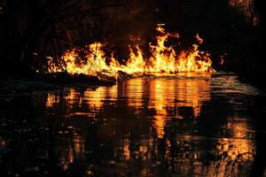 Flames reflected in a river at night, surreal and frightening beauty of fire in nature photo