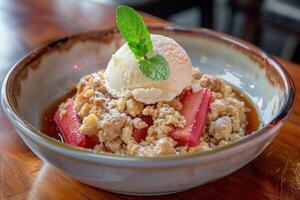 Gourmet rhubarb crumble with a scoop of vanilla ice cream, garnished with a mint leaf in a ceramic bowl, perfect for summer menus and Mothers Day photo