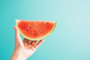 ripe watermelon slice held against a blue to white gradient background photo