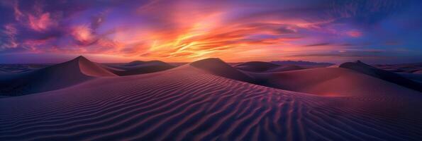 Sunrise paints unusual fractal patterns on undulating desert sand dunes with a vibrant orange and purple gradient sky as backdrop photo