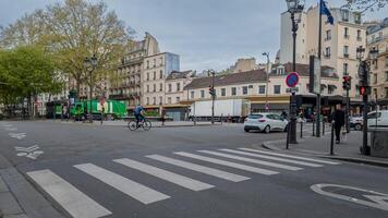 tranquilo ciudad calle escena en París con un ciclista cruce y vehículos, capturar todos los días urbano vida y sostenible transporte, potencialmente útil para viaje o ambiental temas foto