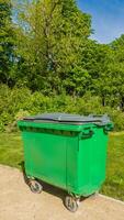 Green waste container on wheels in a sunny park, symbolizing urban recycling and environmental conservation efforts Related to, Earth Day, World Environment Day photo