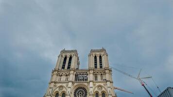 Majestic Notre Dame Cathedral in Paris under restoration with cranes against a cloudy sky, symbolizing cultural heritage and European architecture photo