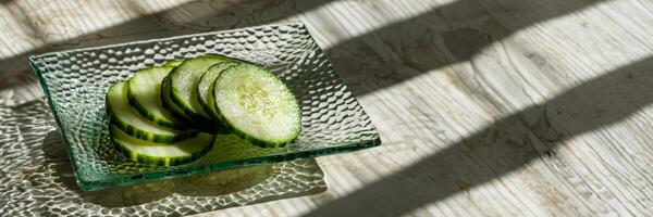 sliced cucumber on a textured glass plate, refreshing green, backlit by sunlight photo