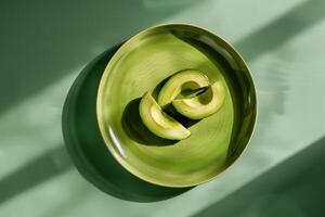 sliced avocado on a bright ceramic plate, minimalist style, top view with copy space photo