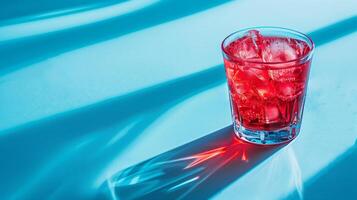 Refreshing iced beverage in a glass on a blue surface with dynamic shadows, ideal for concepts related to summer refreshments or cocktail hour photo