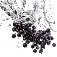 Fresco negro uvas salpicaduras dentro agua con dinámica gotas, Perfecto para conceptos relacionado a refresco, sano comiendo, y verano bebidas foto