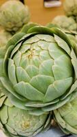 Close up of a fresh green artichoke on display at a farmers market, ideal for vegetarian cuisine and healthy eating content, related to World Vegetarian Day photo