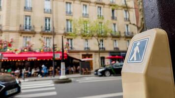 Pedestrian crossing signal button with a blurred Parisian cafe backdrop, symbolizing urban lifestyle and European city tourism photo