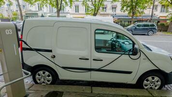 White electric delivery van charging at an urban roadside station, representing sustainable transportation and eco friendly logistics photo