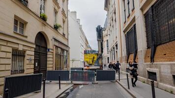 Pedestrians strolling through a quaint Parisian alley with construction in the background, capturing urban life in Paris, France, on April 14th, 2024 photo