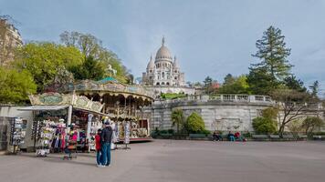 brillante primavera día a Montmartre con turistas cerca recuerdo establos y un Clásico carrusel, sacre canalla basílica en el fondo, París, Francia, abril 14, 2024 foto