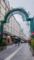 peatones paseo debajo el vino cubierto arco de marche montorgueil en París, Francia, capturar el vibrante calle vida en abril 14, 2024, Perfecto para viaje y cultura temas foto