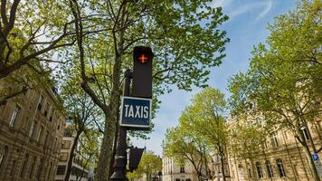 Springtime in Paris, France, with a clear blue sky framing a taxi sign and vibrant green trees along the boulevard, captured on April 14th, 2024 photo