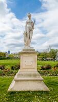 Classic white marble statue of a female figure with a dog in a blooming Parisian park, symbolizing art and history, photographed on April 14th, 2024 photo