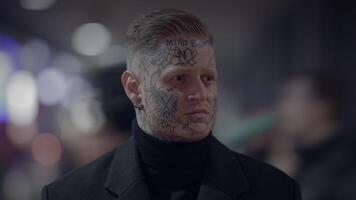 intimidante disidente rebelde hombre con cabeza y cara tatuajes en provocador estilo video