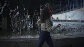 feliz jovem mulher com encaracolado cabelo dançando em cidade rua dentro lento movimento video