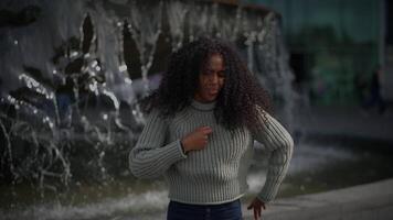 content Jeune femme avec frisé cheveux dansant sur ville rue dans lent mouvement video