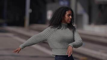 content Jeune femme avec frisé cheveux dansant sur ville rue dans lent mouvement video