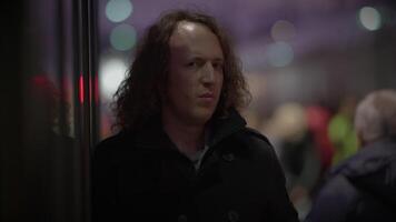 homme avec longue frisé cheveux faire la navette à l'intérieur train station en train de regarder gens video