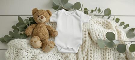 Infant onesie mockup with teddy bear toy and eucalyptus branch on white blanket throw background photo