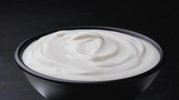 Bowl of sour cream on black background photo