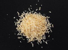 Grated parmesan cheese on black background, parmigiano close up photo