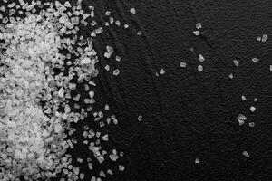 Coarse sea salt on black background, top view photo