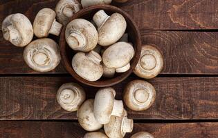 Champignons in wooden bowl on brown background photo