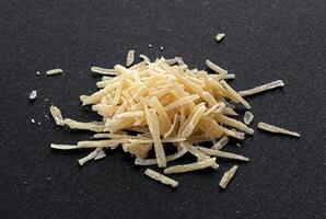 rallado parmesano queso en negro fondo, parmigiano cerca arriba foto