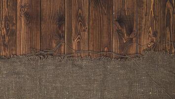 Old burlap fabric napkin on brown wooden background, top view photo