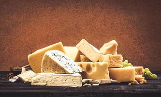 Different types of cheese on black wooden table background photo