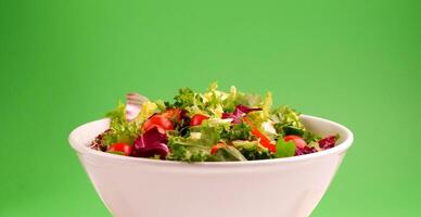 Fresh salad in bowl on green background photo