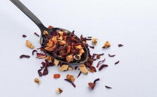 Fruit tea leaves in spoon on white background photo