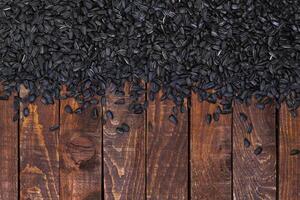 Black sunflower seeds on wooden background photo