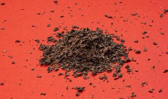 Pile of ground chocolate on red background photo