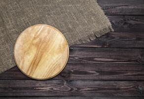 Cutting board on wooden table, top view photo
