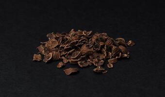 Grated chocolate. Heap of ground chocolate isolated on black background, closeup photo