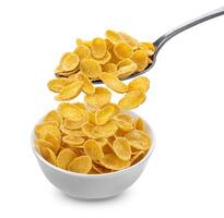 Corn flakes falling from spoon into bowl isolated on white background photo