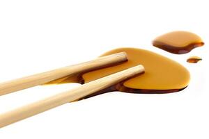 Soy sauce with chopsticks isolated on white photo