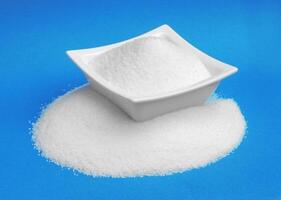 Sugar in bowl isolated on blue background photo