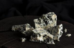 Danish blue cheese on black wooden background, with copy space photo