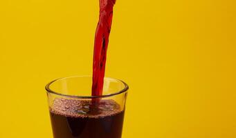 Pouring cherry juice isolated on yellow background with copy space photo