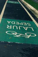 Bicycle lane sign in yellow with solid lines on asphalt road in Indonesia photo